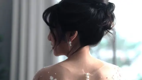 Getty Images A bride with her in an updo looks over her shoulder.