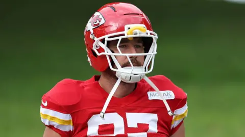 Icon Sportswire via Getty Images Travis kelce wearing a red jersey and a red and white football helmet.