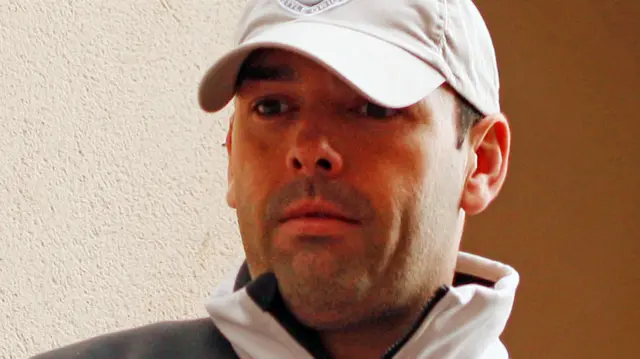 A close-up of Daniel Kinahan's face shows him with facial stubble and wearing a white cap.
