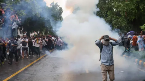 EPA A person walking away as Indian security personnel use tear gas and lathi charge as they attempt to stop Cockroach Janta Party's(CJP) supporters during a march toward the Parliament in New Delhi, India, 20 July 2026.