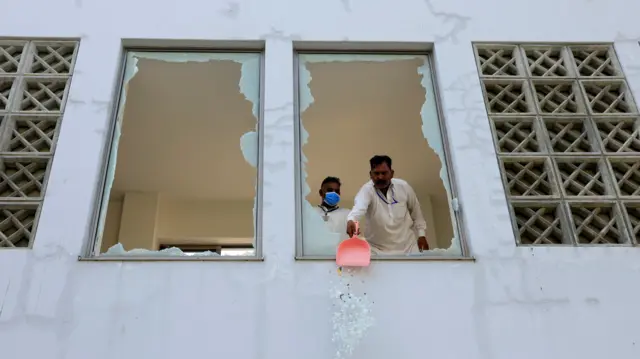 PIMS Hospital staff peek through shattered glass windows after a fire that killed 14 infants.