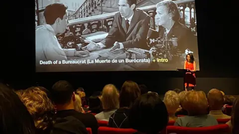 LOLAFF Founder Ketty Rodriguez introducing a screening of Cuban film, Death of a Bureaucrat in a cinema