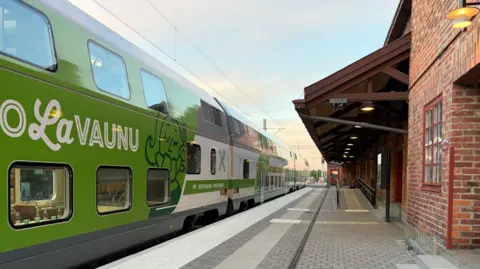 VR A green and white double-decker Finnish VR train pulls into a railway station.
