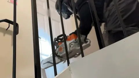 Police use chainsaw to force door open