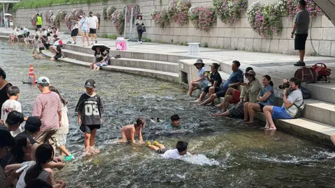 Getty Images  Local residents and tourists cool off at Cheonggyecheon stream