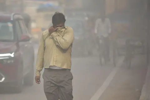 NurPhoto via Getty Images A pedestrian on a road through a haze of dust pollution from a nearby construction site in Hyderabad