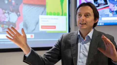 LSE Will Venters waves his hands while making a presentation. 