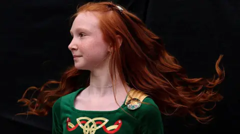Reuters A young girl with red hair, wearing a green velvet Irish dancing outfit