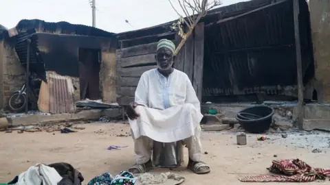 Reuters A man sits in front of burnt out remains in a Woro village in Nigeria 