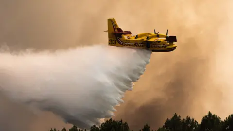 AFP via Getty Images A Canadair firefighting plane drops water on a fire in the Gironde region of France in July.