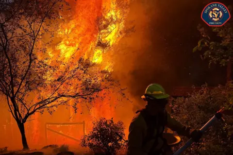 EPA/Shutterstock A member of the Spokane Valley Fire Department battles a fire northeast of Spokane, Washington