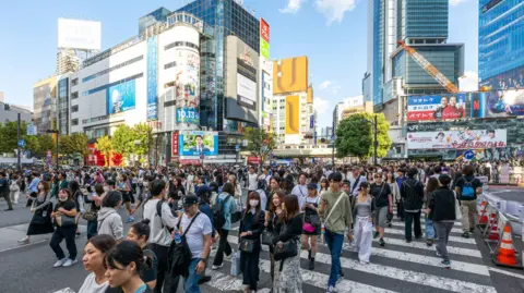 AFP via Getty Images Pedestrians in central Tokyo