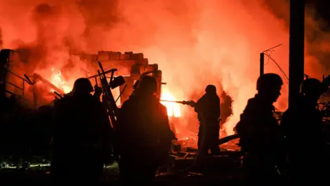 Reuters Firefighters work at the site of a car garages of residents which were hit by an overnight Russian missile strike, amid Russia's attack on Ukraine, in Zaporizhzhia, Ukraine.