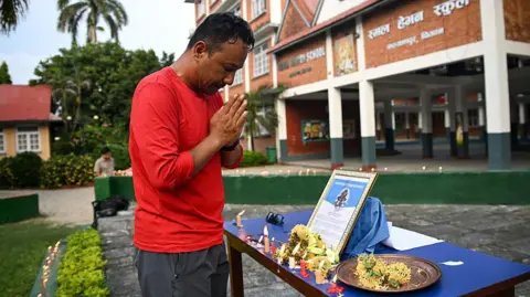Getty Images A man wearing a red shirt offering his condolences