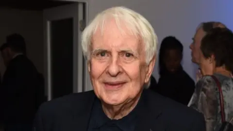 Getty Images A man with white hair looks at the camera