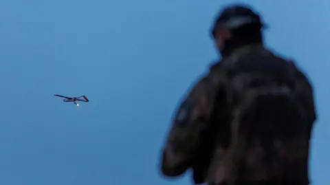 Reuters A Ukrainian soldier operating a drone, which is flying in the air in the background
