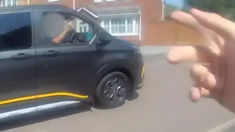 Police officer's hand hailing a lift from a black van.