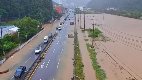 Reuters Cars pass through a severely flooded highway in Geoje, Gyeongsang, South Korea