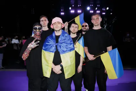 Getty Images Kalush Orchestra pictured at the Eurovision Song Contest, draped in the Ukrainian flag