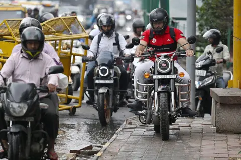 AFP via Getty Images A  motorist riding on a pedestrian footpath along a bridge in New Delhi. 