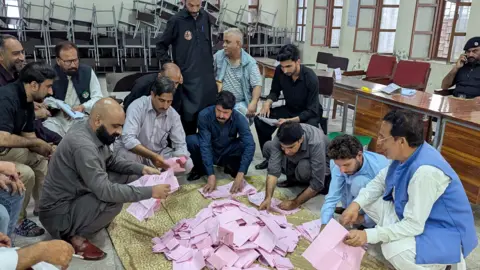 EPA Election officials crouch round a pile of pink ballot papers as they count votes in the local elections in Muzaffarabad, the capital of Pakistan-administered Kashmir.
