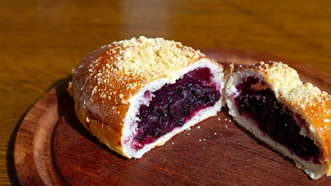 Alamy A berry-filled bun cut in two halves on a wooden plate (Credit: Alamy)