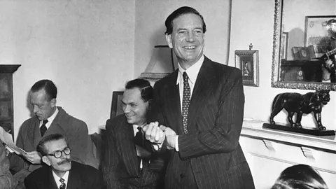 Getty Images A black-and-white photo of Kim Philby in a suit speaking to a room of men (Credit: Getty Images)