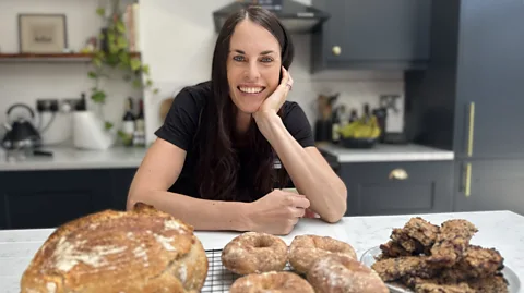 Stephen Parker Melissa Hogenboom poses with homemade bread, bagels and oat bars on a kitchen counter (Credit: Stephen Parker)