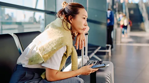 Getty Images Woman sitting with her luggage in an airport terminal (Credit: Getty Images)